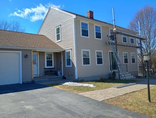Front of a two-story home with completed beige vinyl siding and replacement windows
