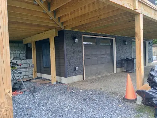 Second view of dark siding installation around garage doors under a deck