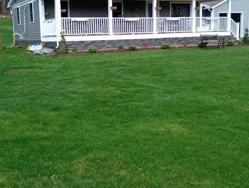 Completed covered porch with gray siding, white railing, and stonework