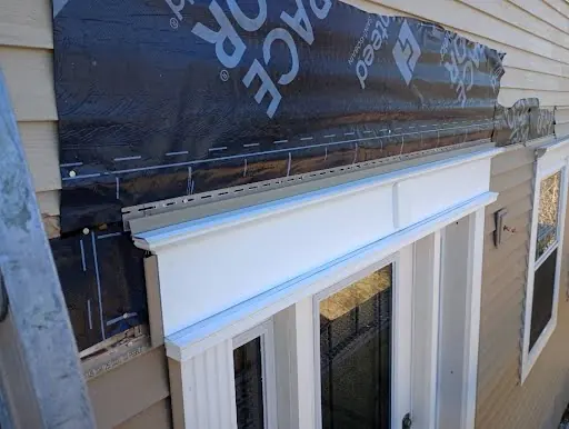 Custom metal flashing and white trim being installed above a front entry door