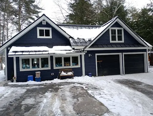 Completed garage and home renovation with dark siding and white trim