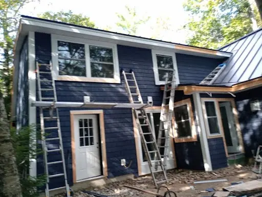 Dark siding installation underway on the garage elevation