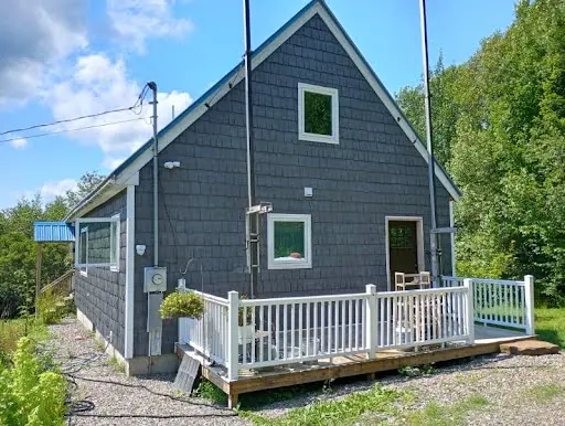 Completed blue-gray shingle siding around the white-railed deck