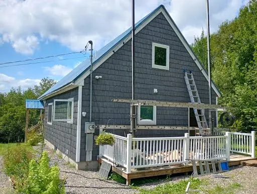 Completed blue-gray shingle siding across the gable end of the home