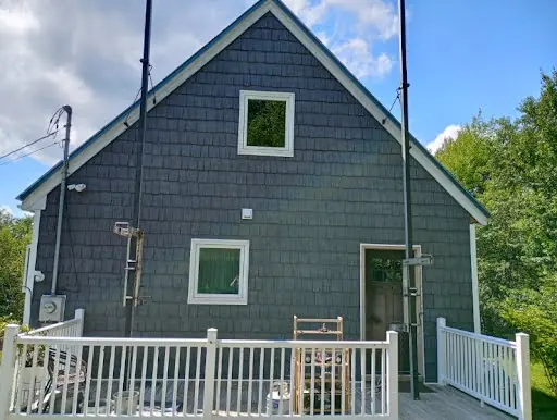 Rear gable after blue-gray shingle siding and white window trim installation