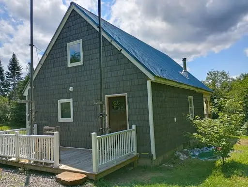 Completed blue-gray shingle siding on the side of a Maine home