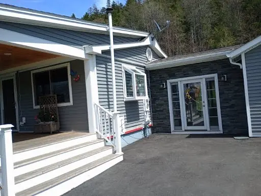 Completed gray siding and dark stone accent around a home entry